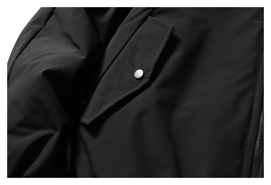Close-up of a black jacket's angled flap pocket with a silver snap closure.