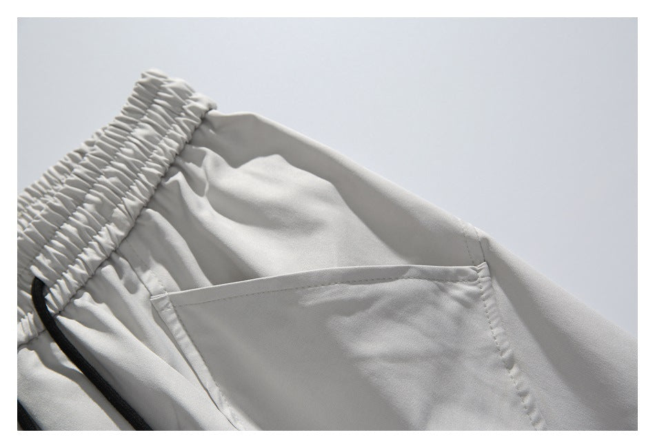 Close-up of a side pocket and gathered elastic waistband on light gray shorts.