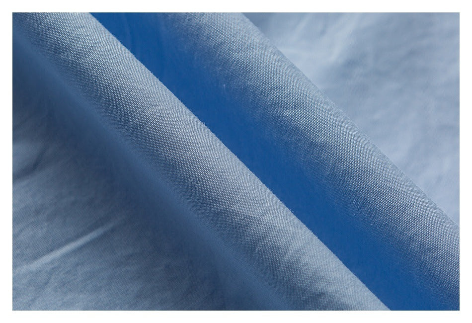 Close-up of blue fabric folds with a fine woven texture and subtle tonal variations.