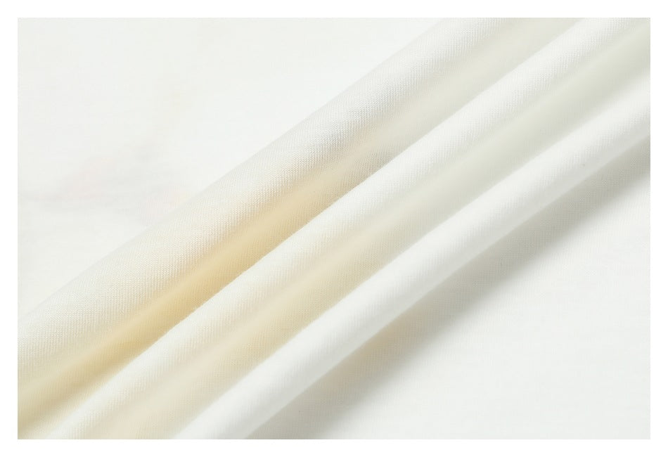 Close-up of white fabric folded into diagonal drapes, showing its fine surface texture.