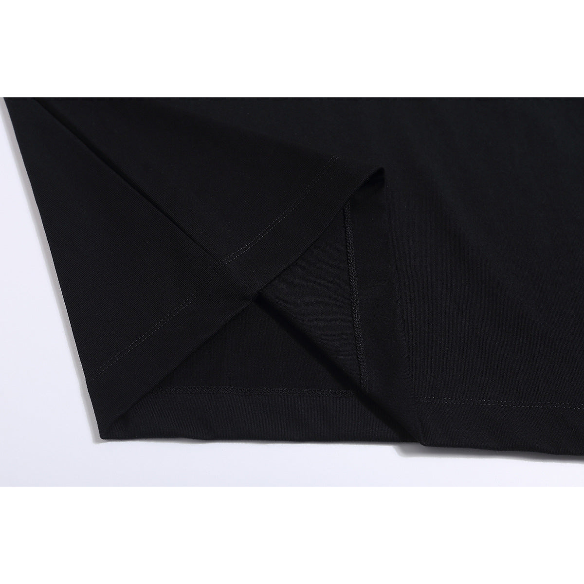 Close-up of a black T-shirt’s folded hem and visible stitching.