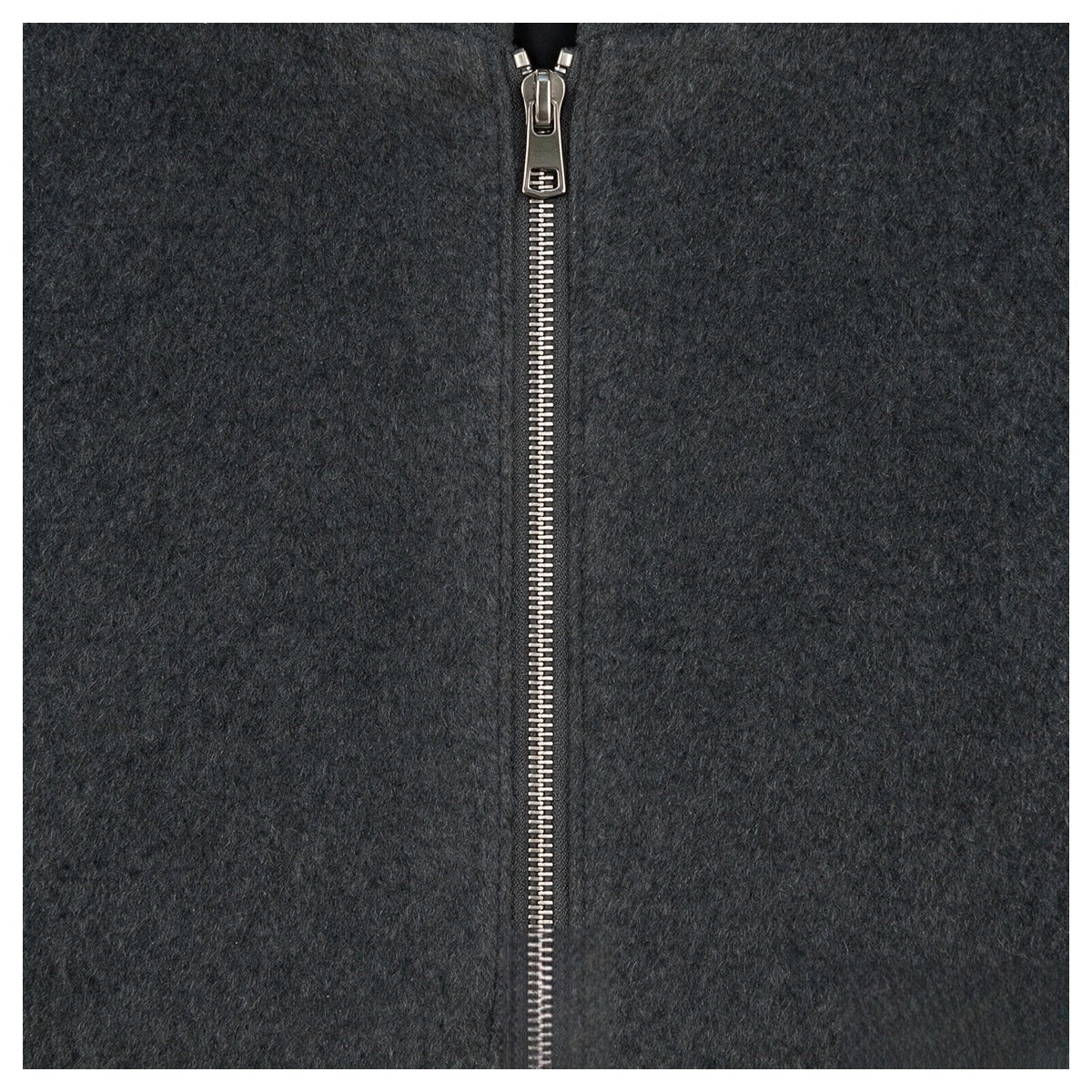 Close-up of a silver metal zipper running through charcoal gray textured fabric.