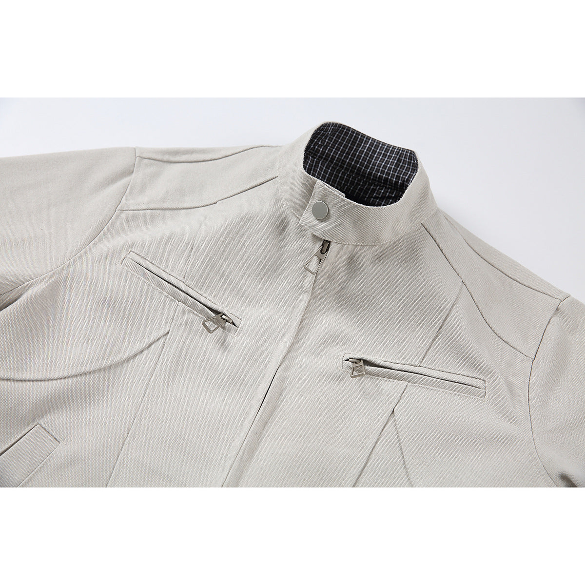 Close-up of a light beige jacket front showing a stand collar, center zipper, and two horizontal zip pockets.