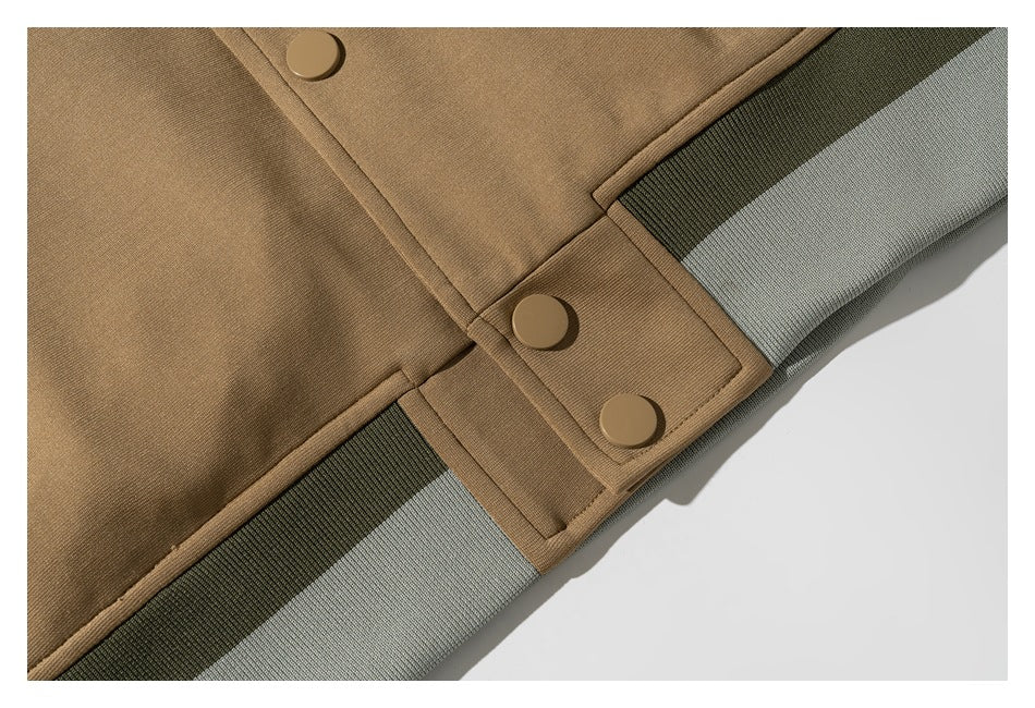 Close-up of the tan jacket's snap-button placket and ribbed gray-green hem trim.