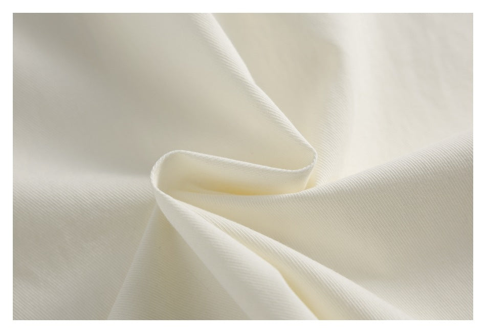 Close-up showing the fine diagonal texture of ivory garment fabric.