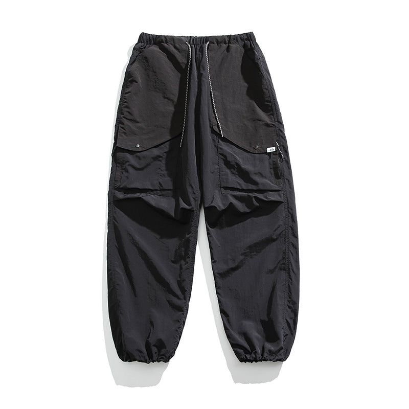 Black cargo pants flat lay with striped drawstring, snap flap pockets, side zip pockets and gathered hems