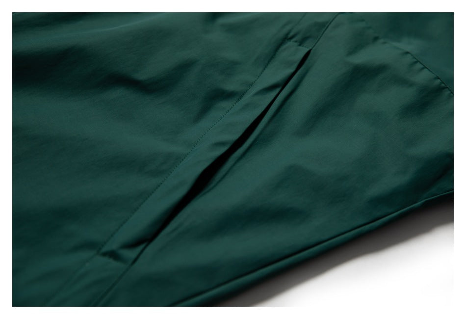 Close-up of dark teal garment fabric showing a narrow seam opening and stitched edge.