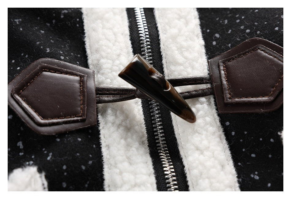 Close-up of a dark toggle closure and zipper between white trim on a black speckled jacket.