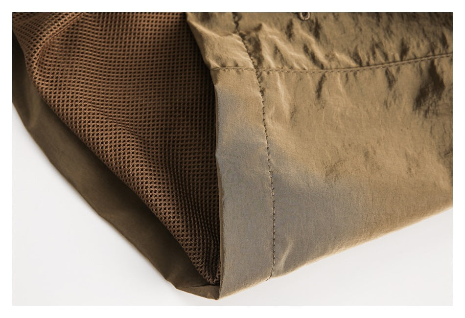 Close-up of brown shorts showing a mesh-lined pocket opening and stitched edge.