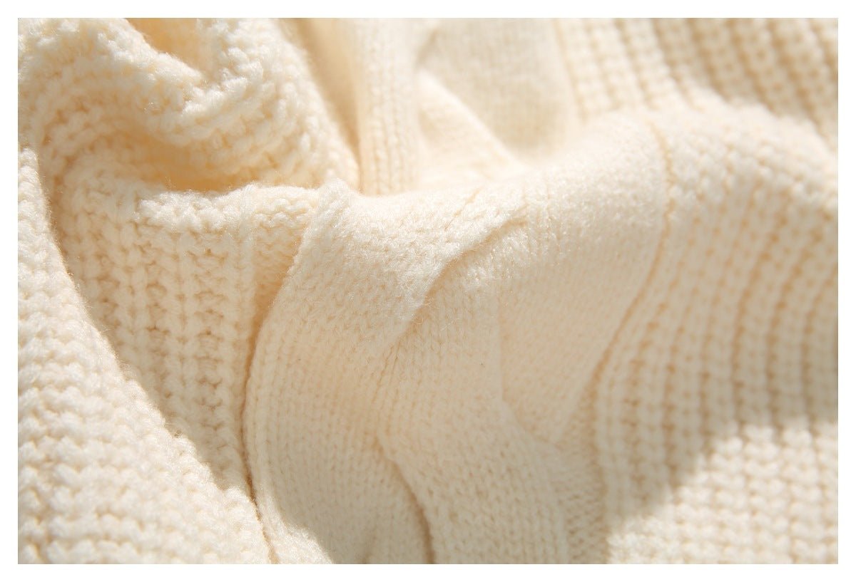 Close-up of the cream sweater's textured knit and a raised knitted seam.