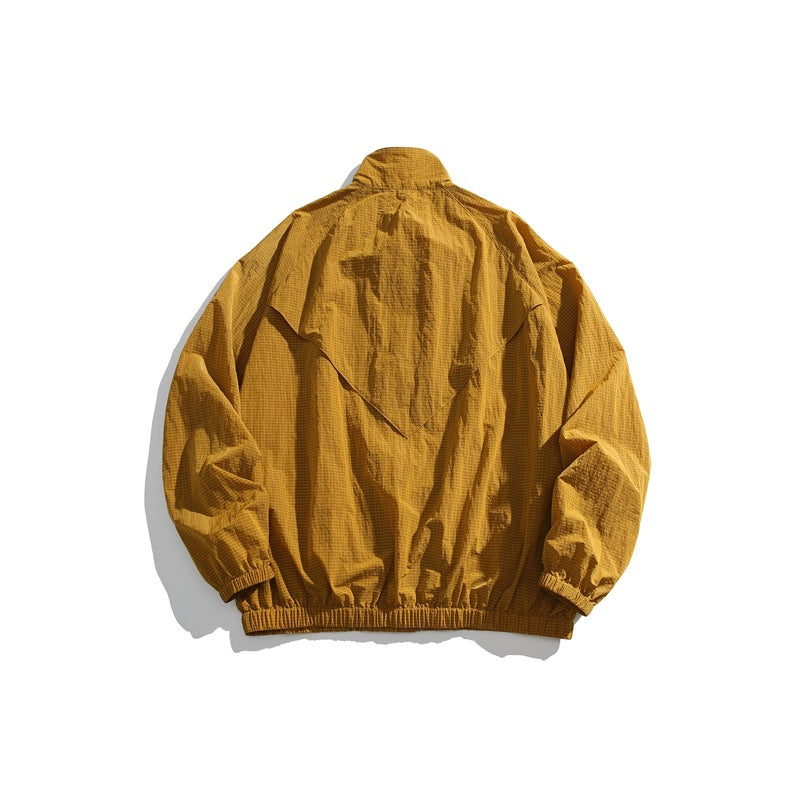 Mustard yellow jacket shown from the back, with a layered flap, high collar, elastic cuffs and hem.
