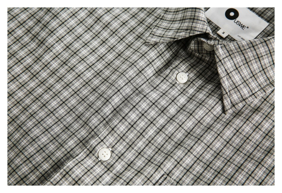 Close-up of the gray plaid shirt's pointed collar, white buttons, and front placket.