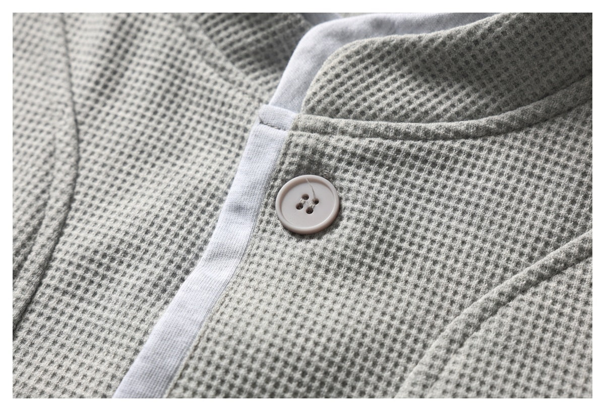 Close-up of the light gray stand collar, textured fabric, and a pale front button.