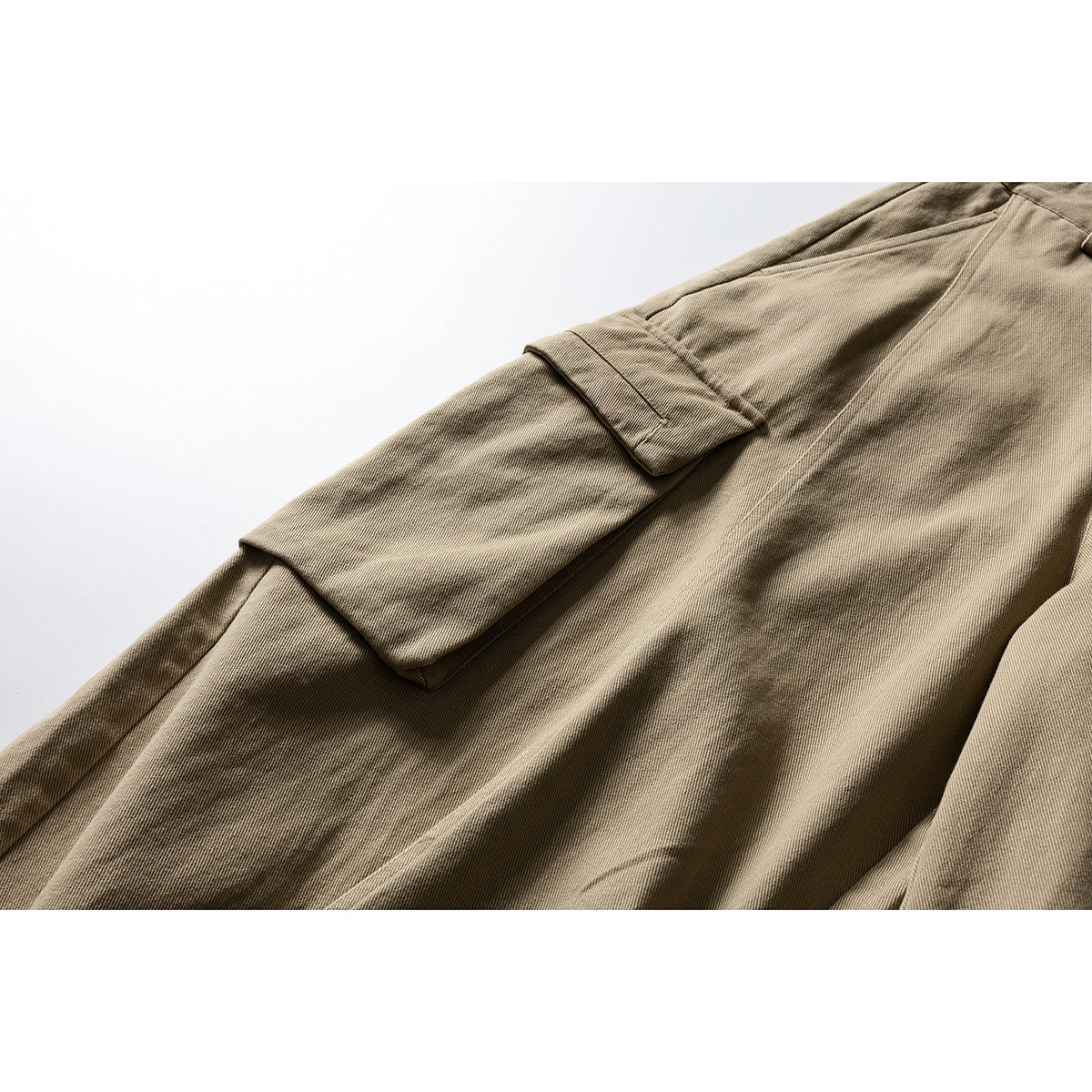 Close-up of a flap cargo pocket and seams on khaki trousers.