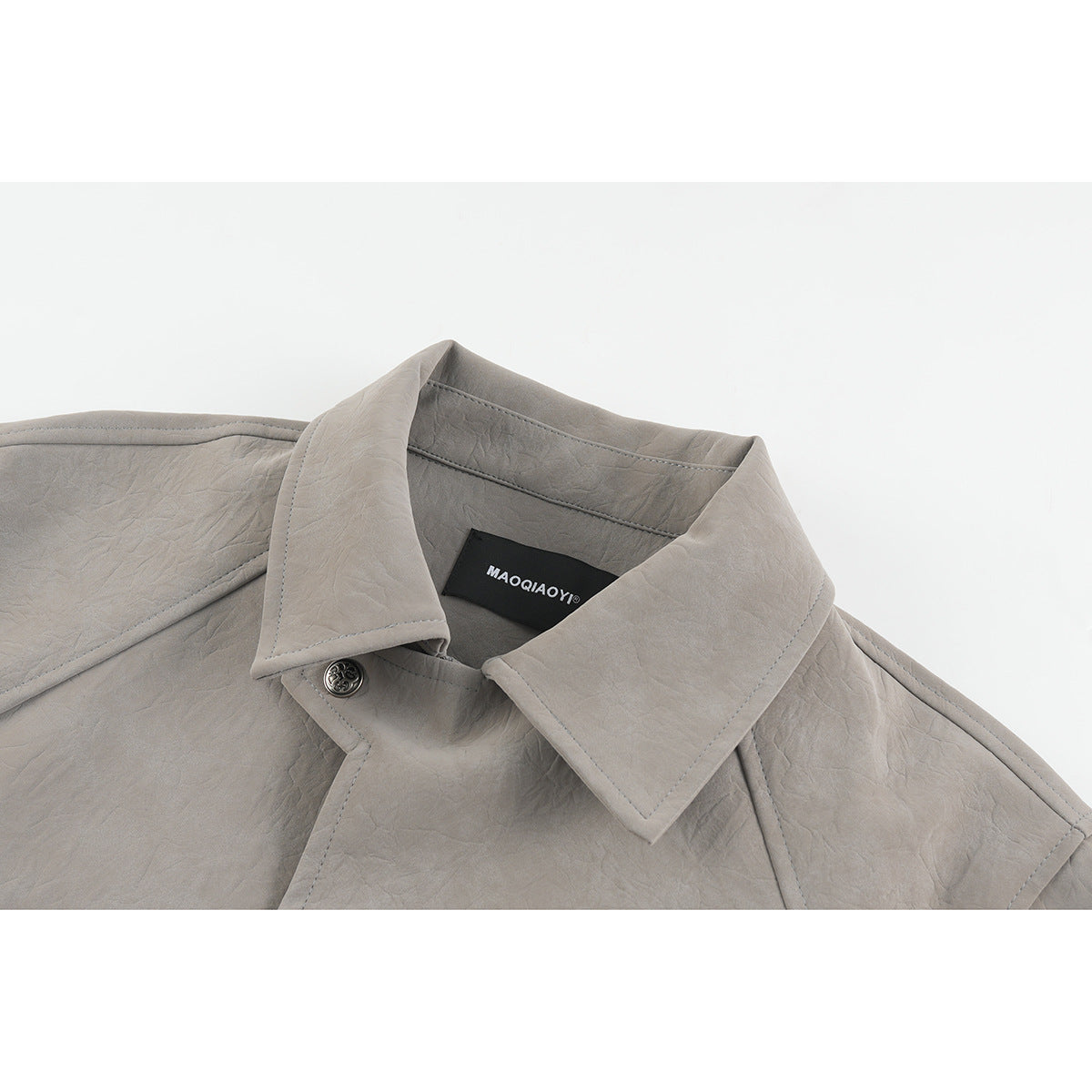 Close-up of a taupe-gray jacket's pointed collar, stitched seams, and metal button; a black neck label is visible.