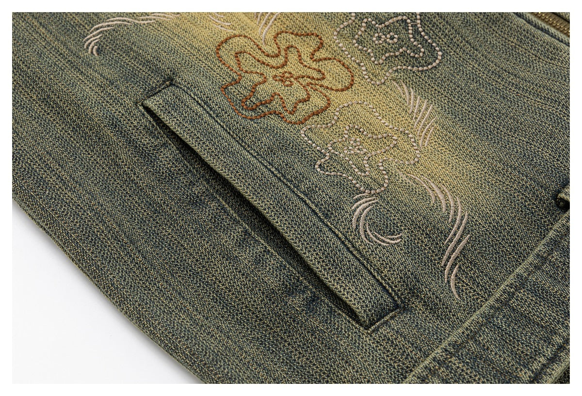 Close-up of floral embroidery and a welt pocket on textured olive-gray fabric.