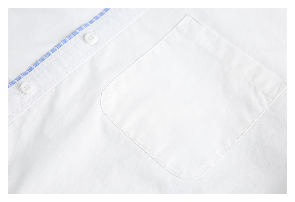 Close-up of a white shirt's chest pocket, buttons, and blue-striped inner placket trim.