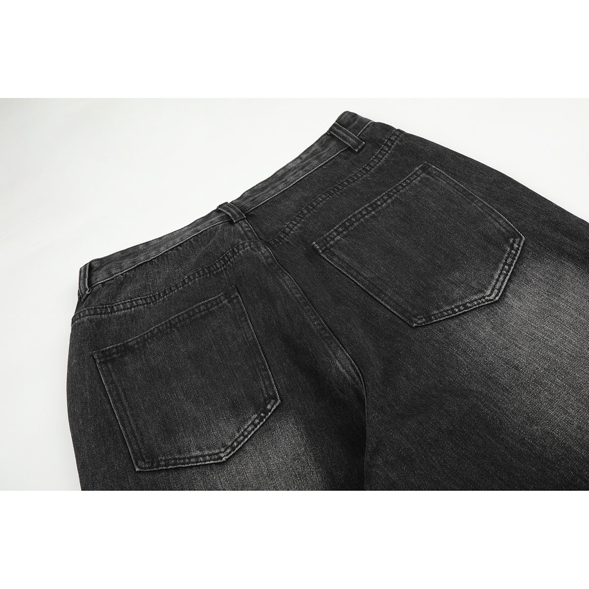 Close-up of the back of charcoal-black jeans with two patch pockets and belt loops.