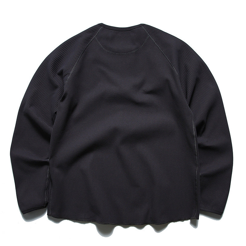 Back view of a dark charcoal long-sleeve waffle-knit crewneck shirt with raglan seams.