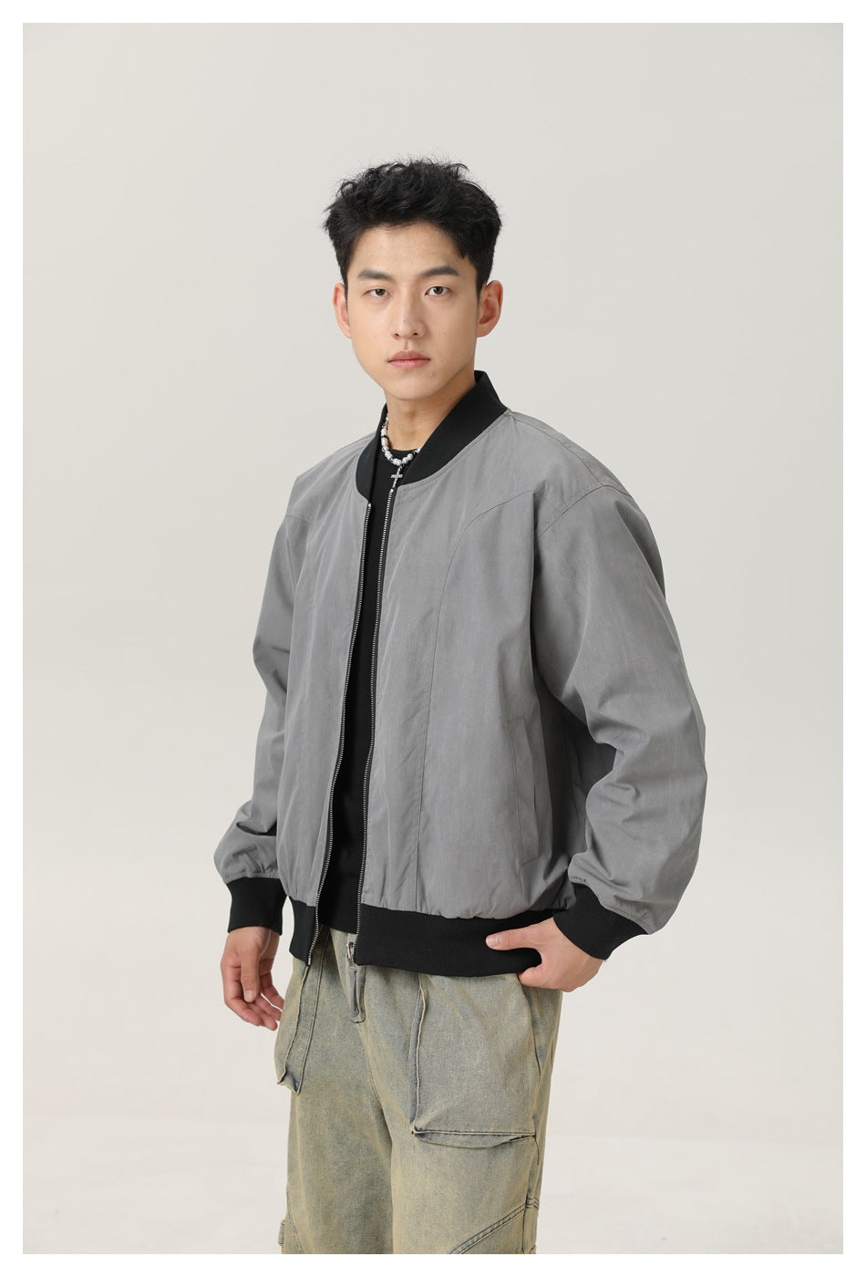 Model wearing a gray zip-front bomber jacket with black ribbed trim, shown from the front at a slight angle.