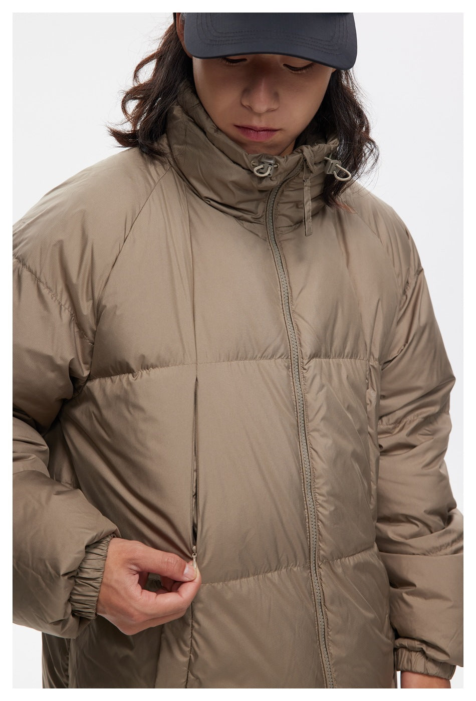 Close-up of the taupe puffer jacket's high collar, front zipper, quilted panels, and side pocket zipper.