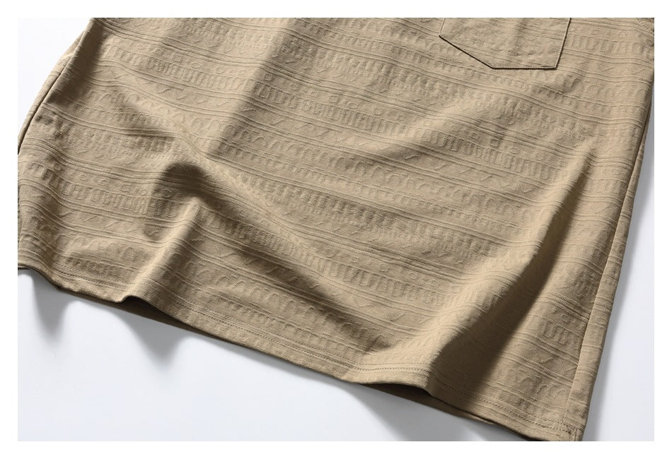 Close-up of the tan shirt's patterned fabric and stitched lower hem.