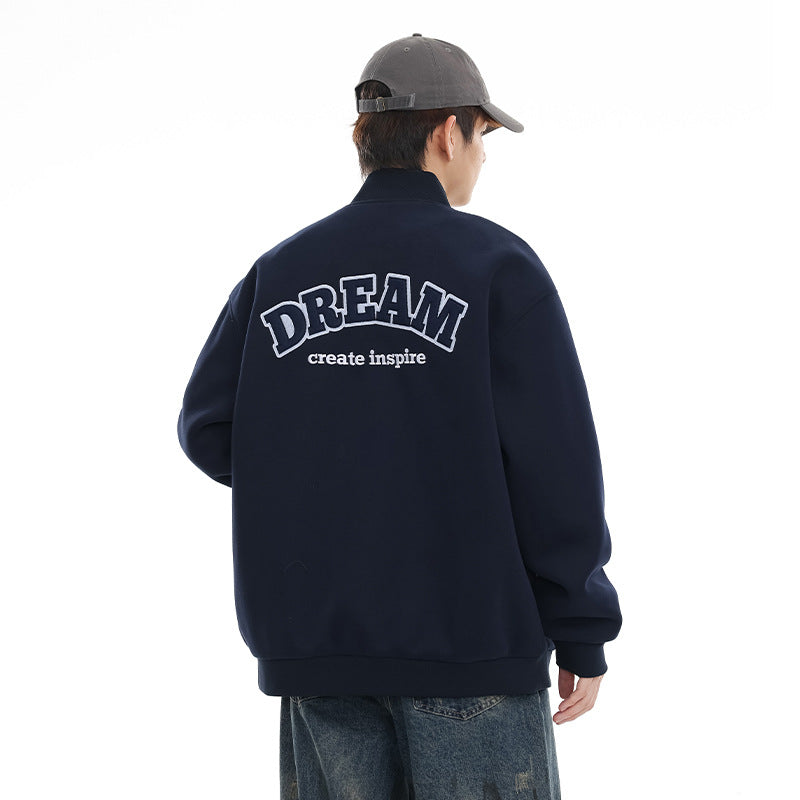 Back view of a navy varsity jacket with large embroidered-style DREAM lettering and smaller text.