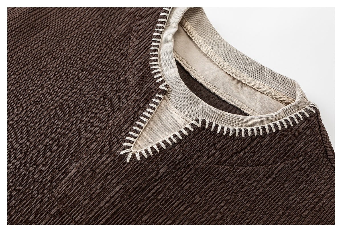 Close-up of a brown ribbed top's round neckline with a beige inset and cream blanket stitching.
