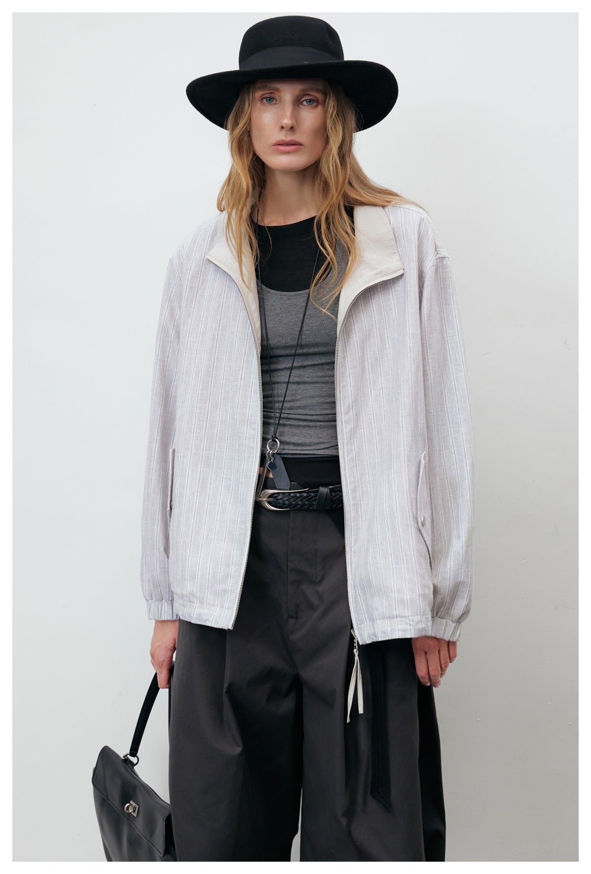 Model wearing an open pale gray vertically striped jacket with a cream collar, zip front, and elastic cuffs.