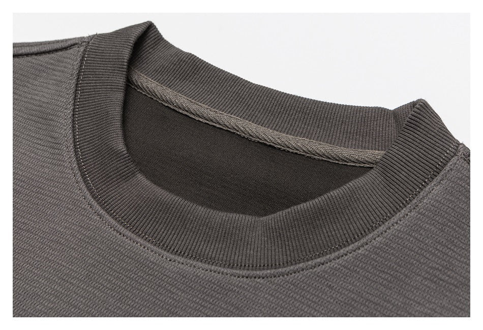 Close-up of the ribbed crew neckline and stitching on a charcoal-gray top.