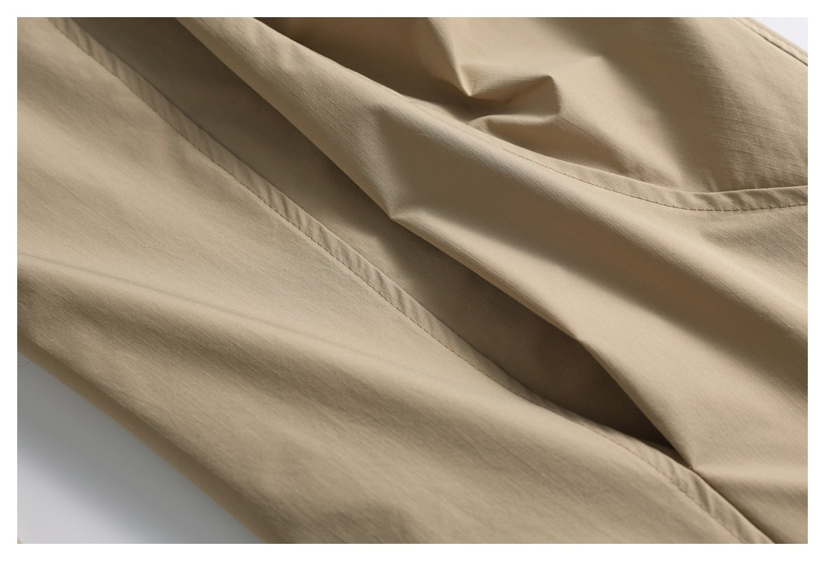 Close-up of tan garment fabric and stitched seams, showing a folded panel.