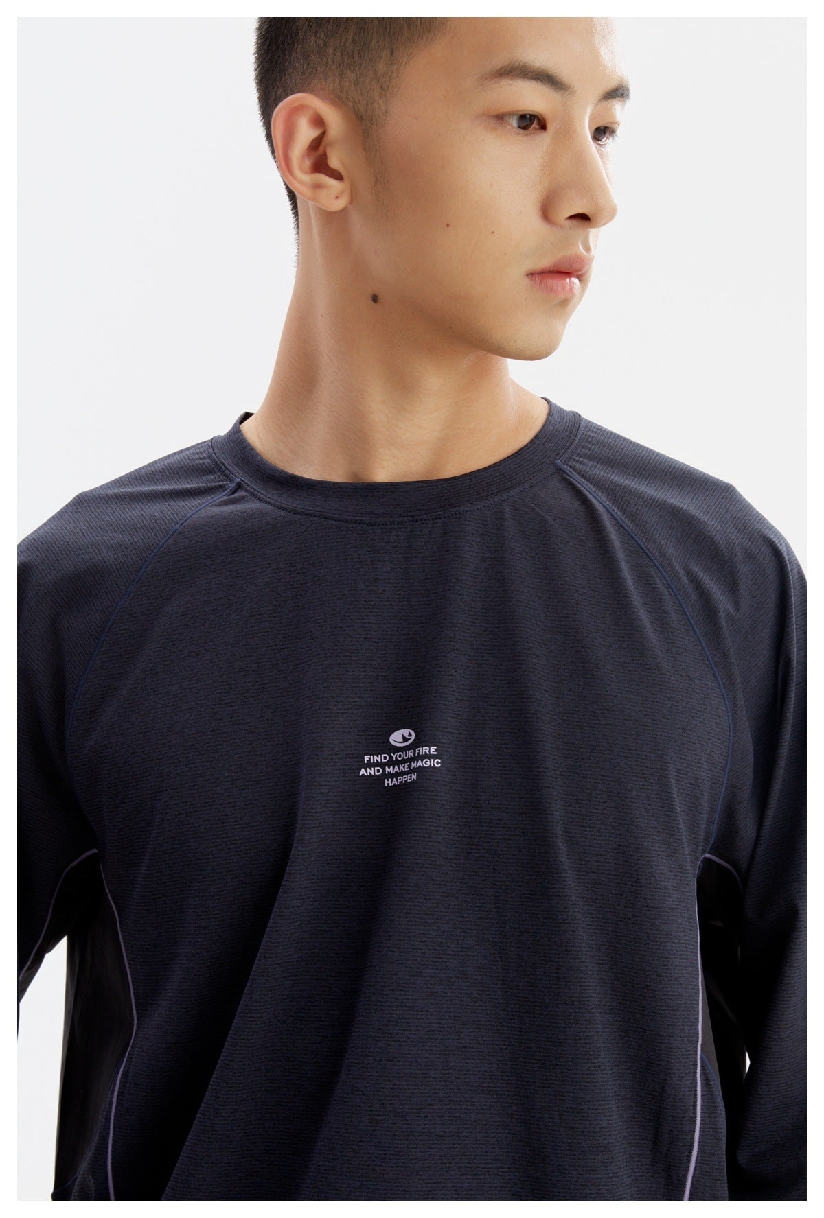 Close view of the navy crewneck's raglan seams, lilac piping, and small white chest slogan print.