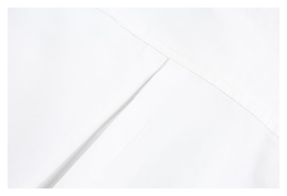 Close-up of intersecting stitched seams on white garment fabric.