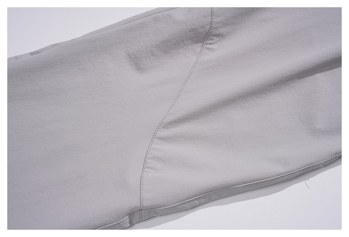 Close-up of light gray trouser fabric with a curved stitched seam and edge stitching.