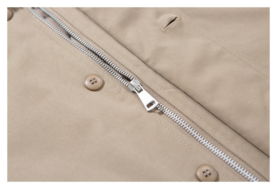 Close-up of a beige coat's metal front zipper, buttons, and stitched buttonhole.