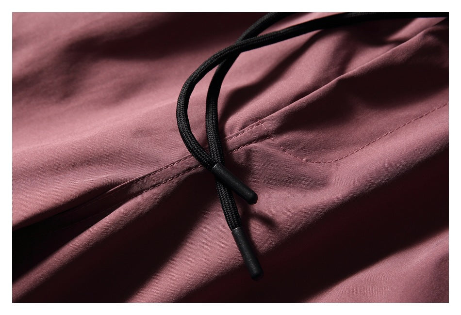 Close-up of black drawcords and stitching on dusty mauve trousers.