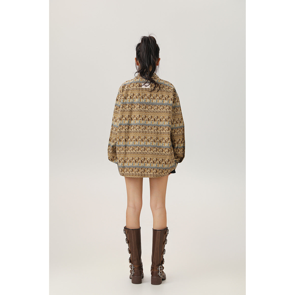 Back view of a model wearing an oversized brown geometric-pattern jacket with blue-gray stripe accents.