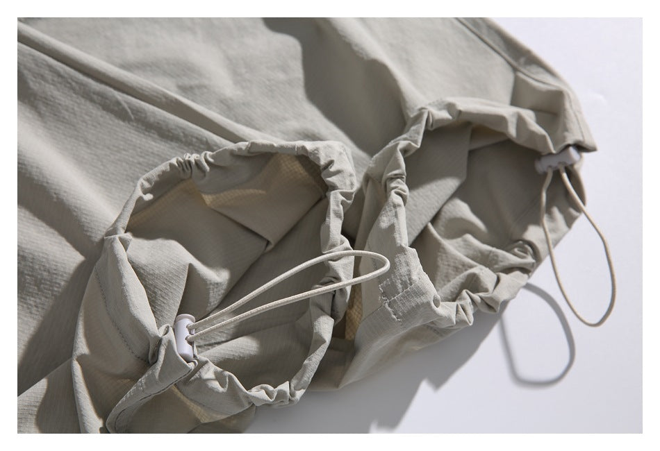 Close-up of an adjustable trouser cuff, showing the drawcord, toggle, and gathered edge.