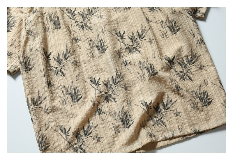 Close-up of the beige shirt's dark botanical print, vertical texture and lower hem.