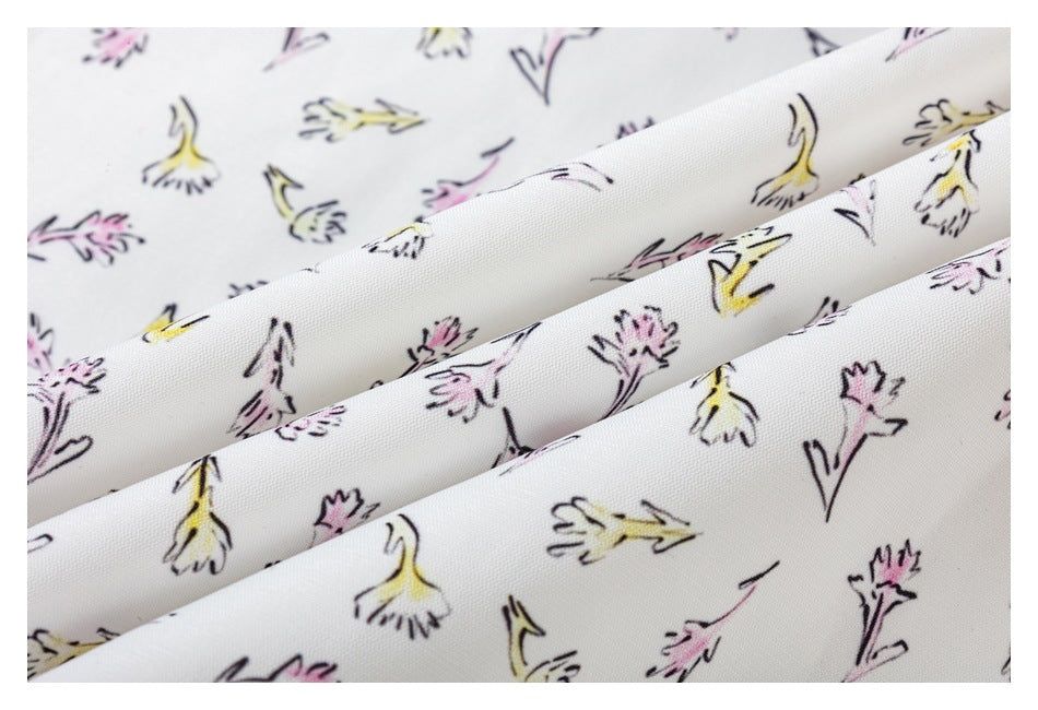 Close-up of white garment fabric with a scattered hand-drawn floral print in pink, yellow, and black.