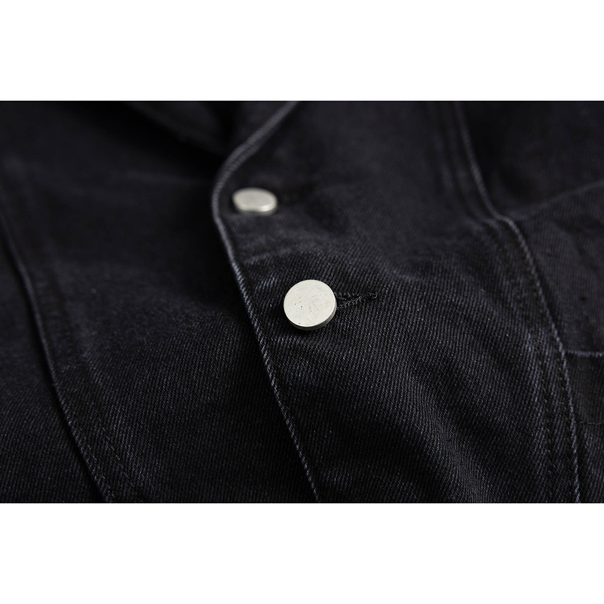 Close-up of two silver metal snap buttons on the black jacket front.