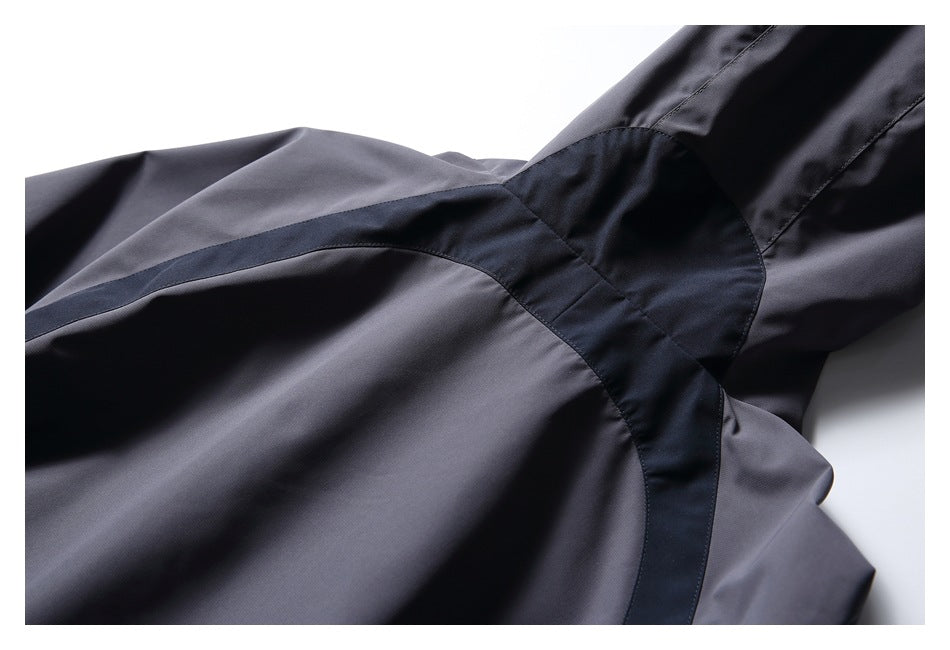 Close-up of a charcoal gray jacket showing dark contrast panels and curved stitching at the sleeve and body.