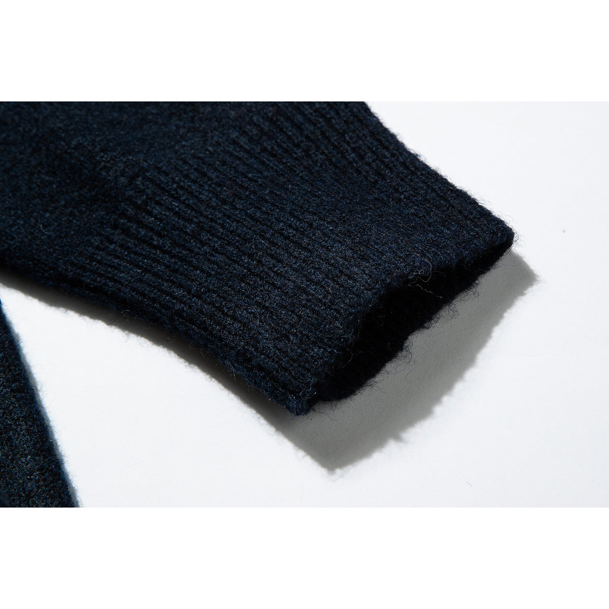 Close-up of the ribbed cuff on a dark navy knit sweater sleeve.