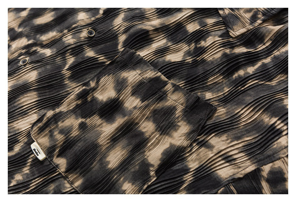 Close-up of a shirt chest pocket, buttons, and black and tan abstract pattern.