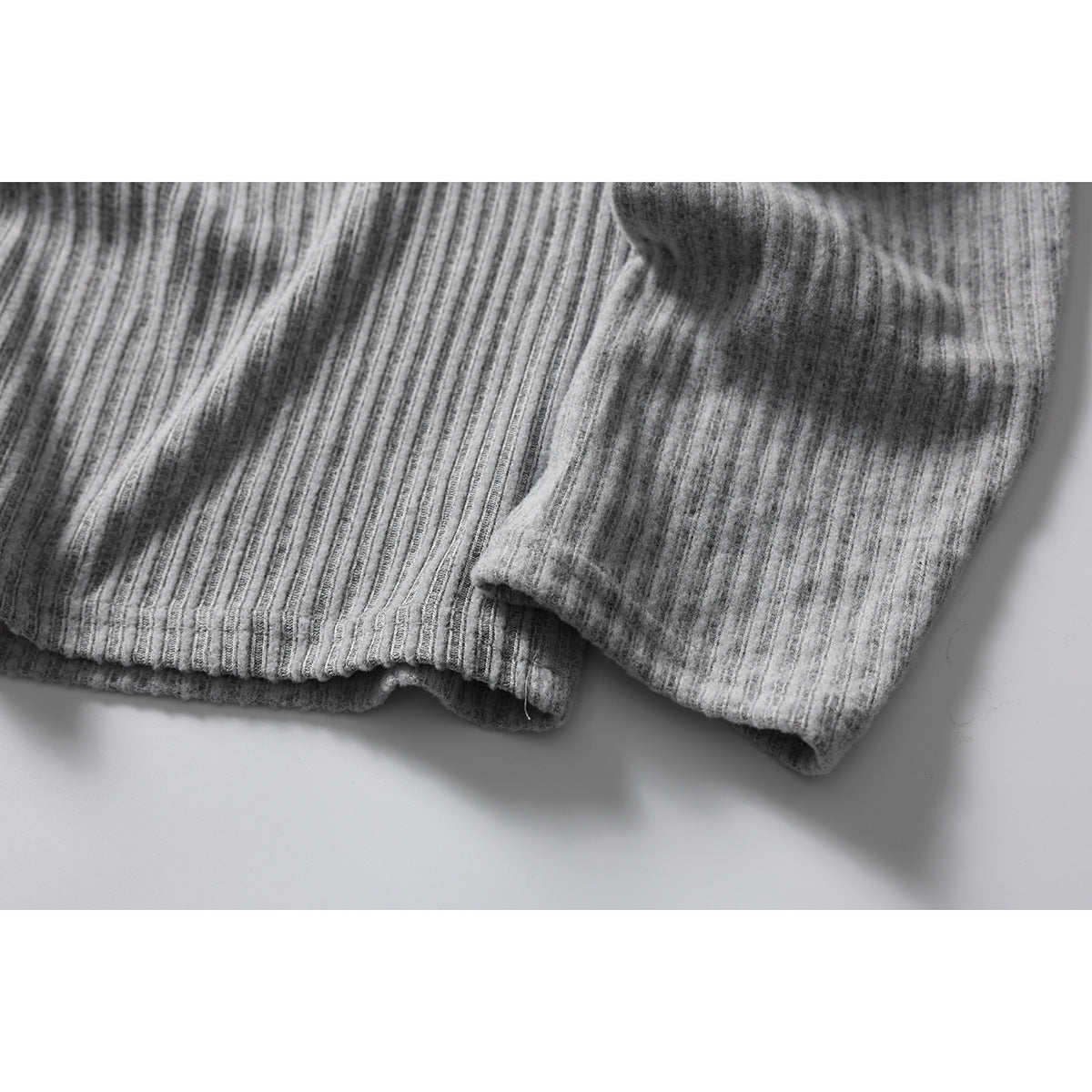 Close-up of the ribbed gray shirt's sleeve and hem edges.