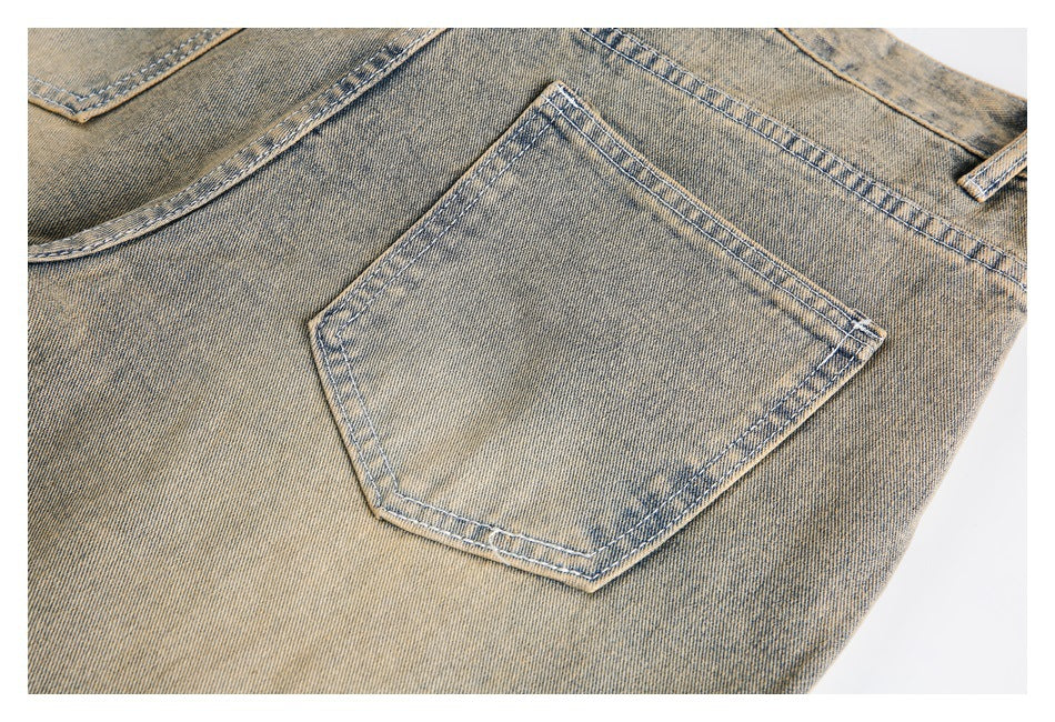 Close-up of a stitched back pocket on faded tan denim jeans.