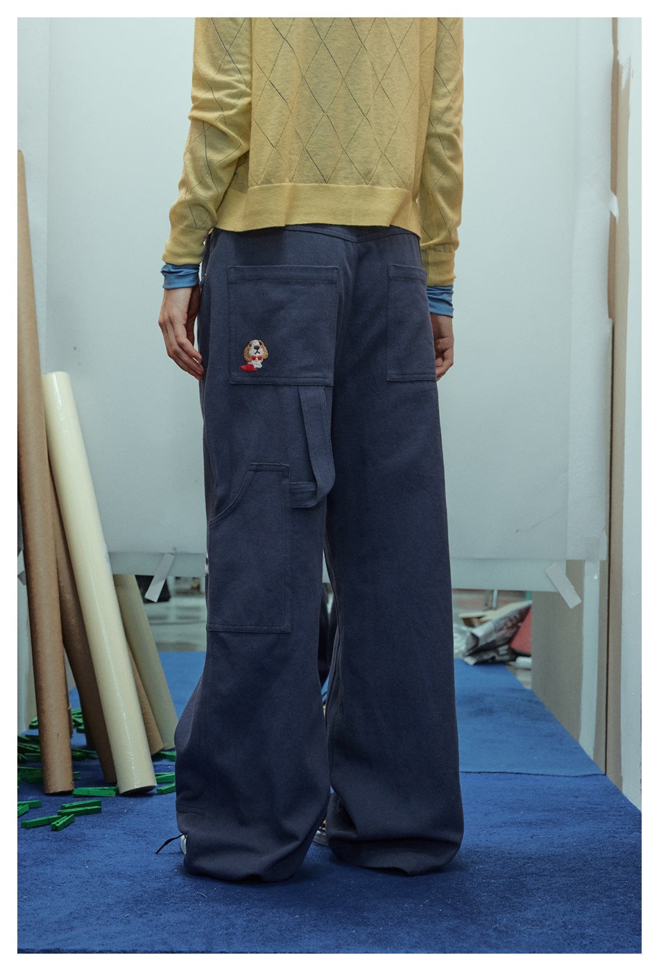 Back view of a model wearing navy wide-leg cargo pants with large pockets and an embroidered character on a pocket.