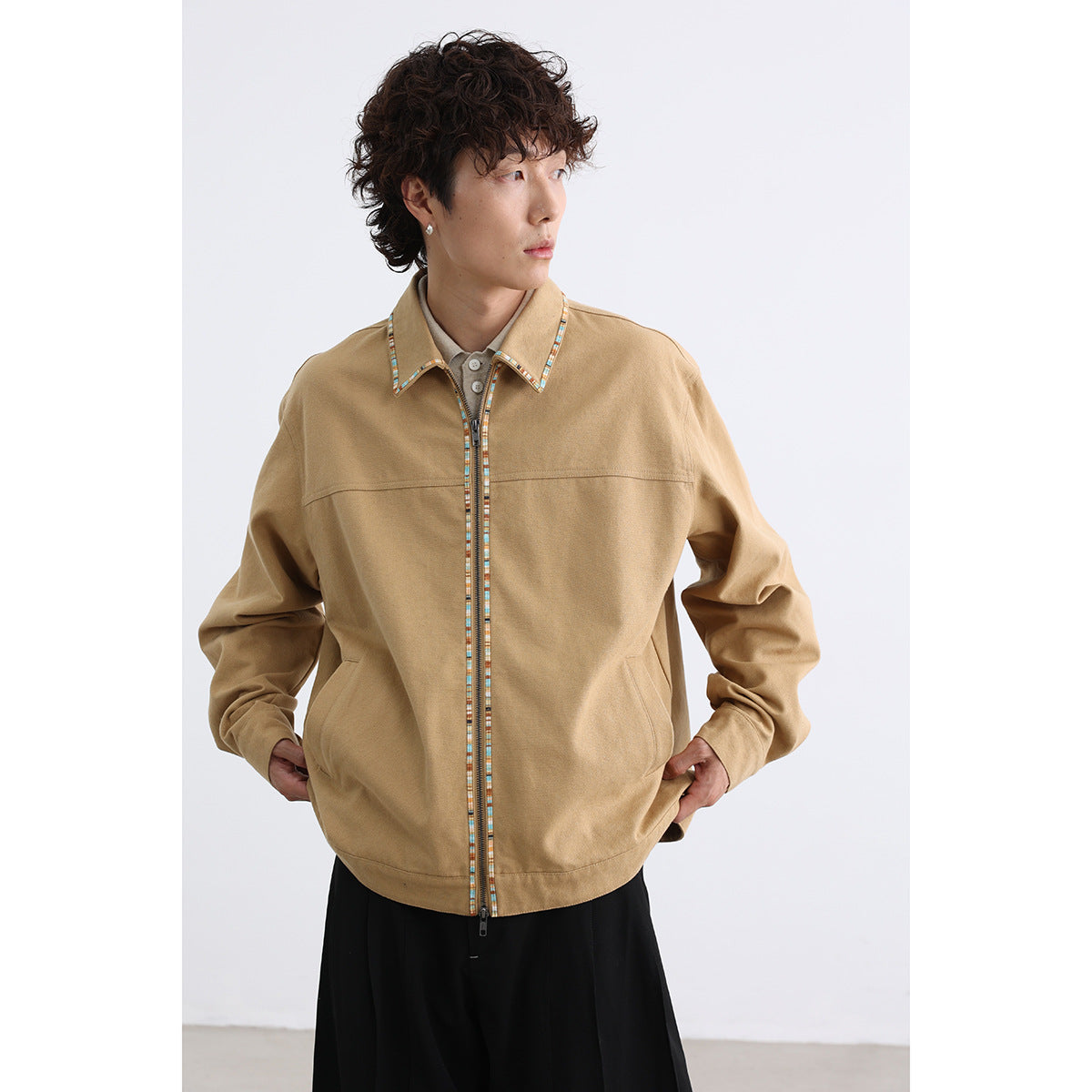 Front view of a model wearing a tan zip-front jacket with multicolor trim and slanted pockets.