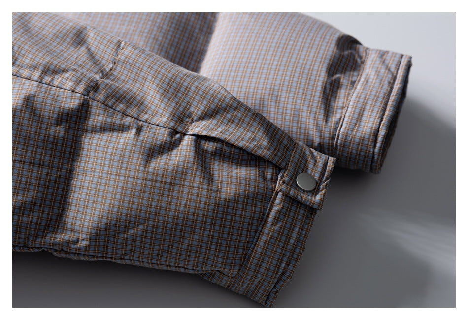 Close-up of a blue-gray plaid shirt cuff with a button and folded sleeve detail.