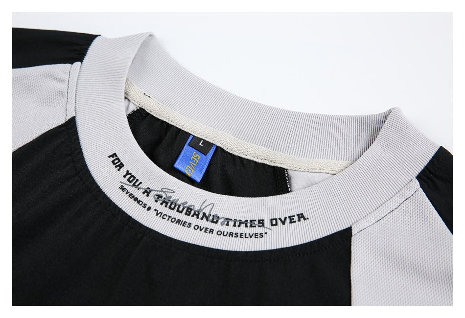 Close-up of a light gray ribbed collar, black shirt body, and blue size label with printed text.
